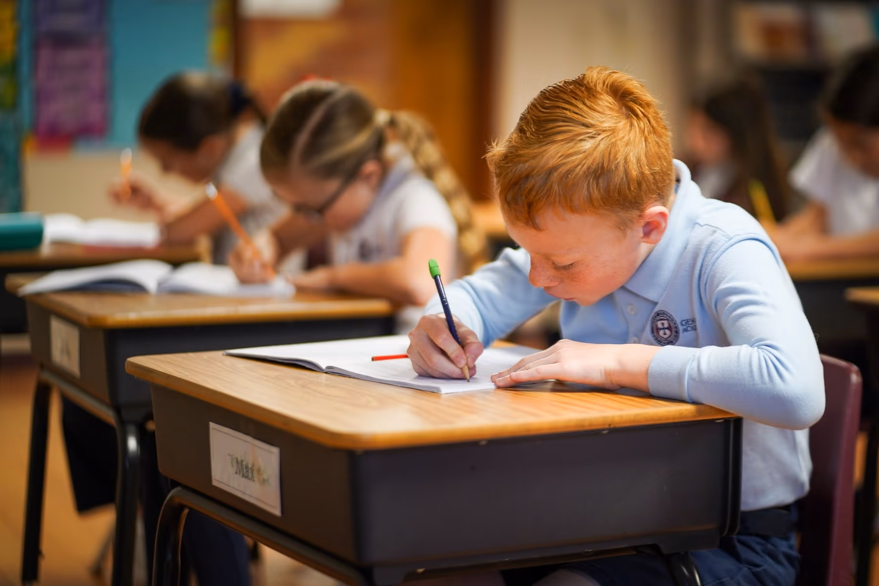 A Geneva Academy student writing at a classroom desk in Roseburg, Oregon